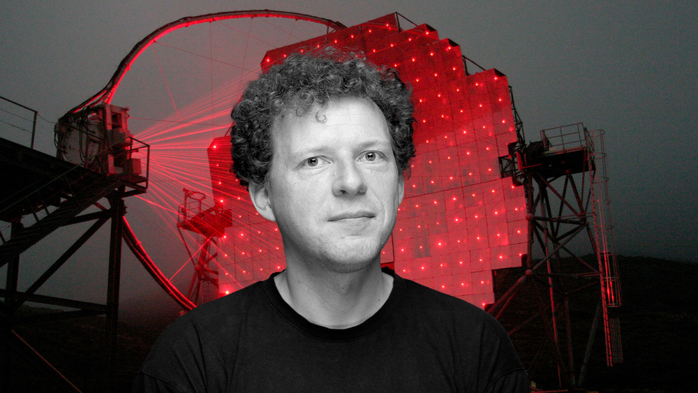 Professor Julian Sitarek against the background of the Cherenkov Telescope illuminated by red lasers