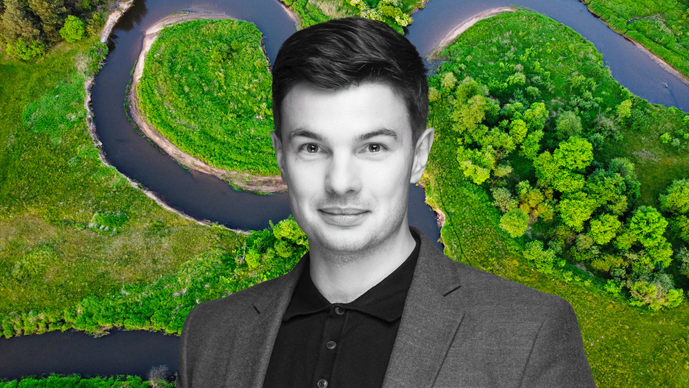 A portrait of Dr Paweł Jarosiewicz against the background of a meandering river