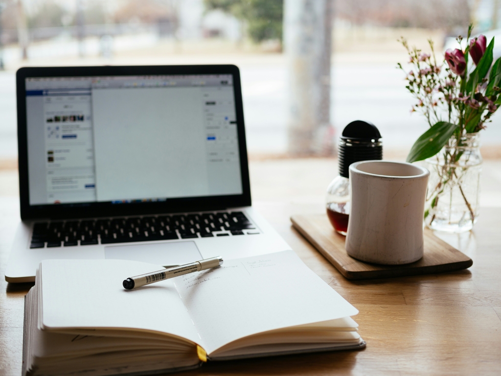 A decoraive element: A laptop on and a notebook lying open next to it