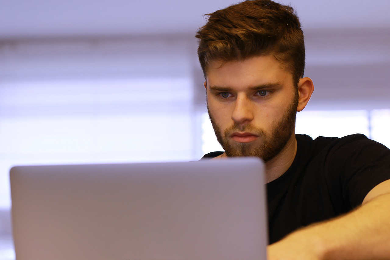 Zdjęcie poglądowe. Chłopak z zainteresowaniem patrzy w ekran komputera.