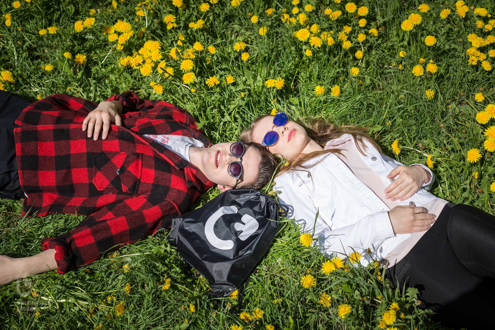 Studenci UŁ leżą na trawie.