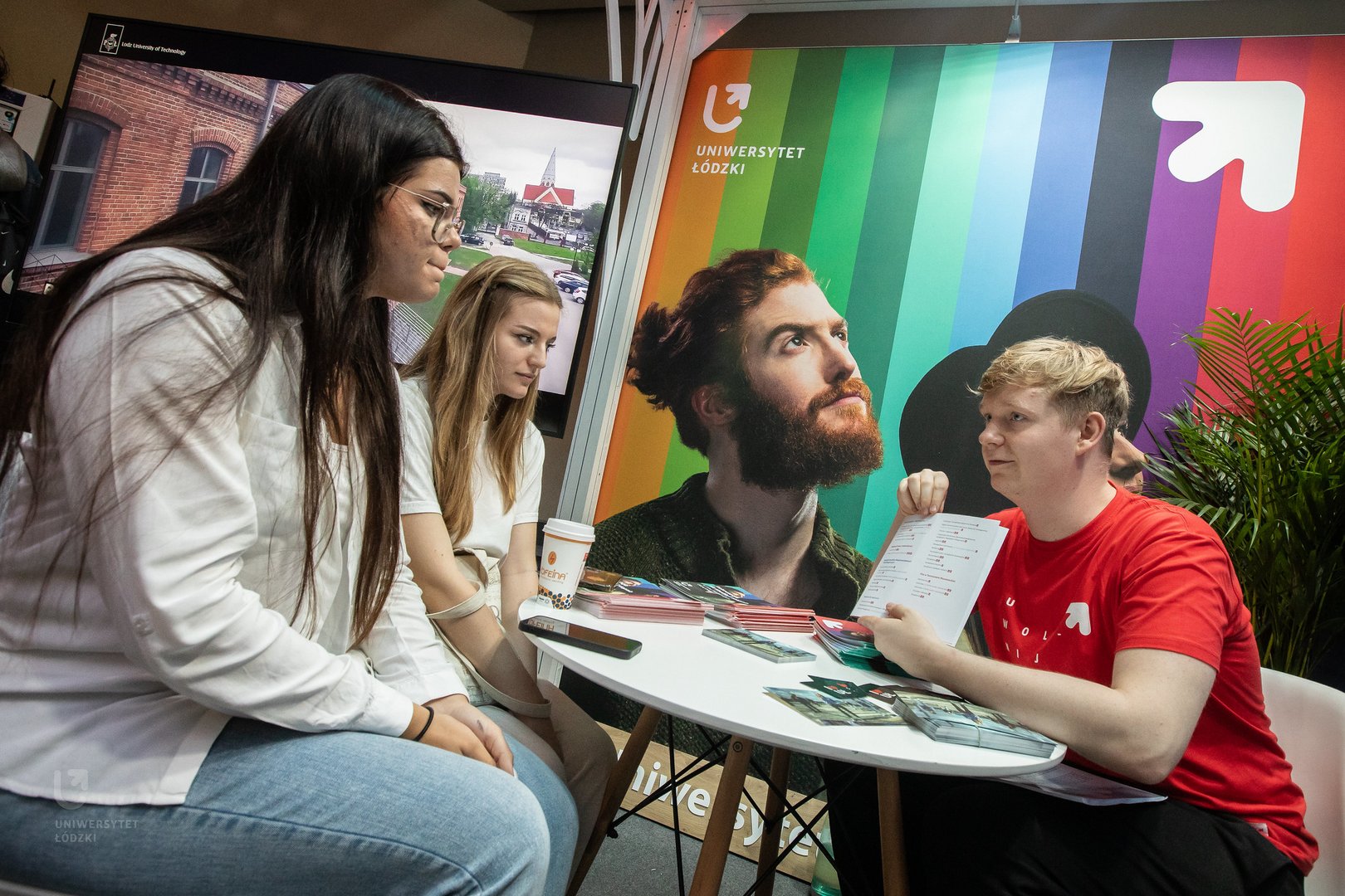 [Translate to English:] A University of Lodz student showing the study offer to potential candidates.