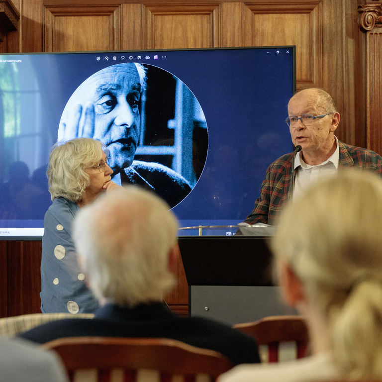 Fotografia osób stojących przy mównicy 