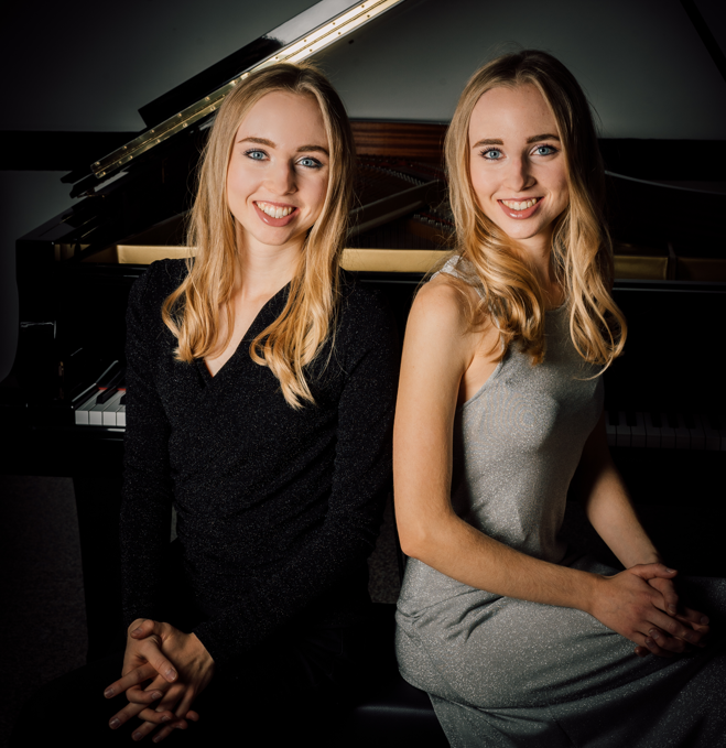 dwie siostry bliźniaczki blondynki siedzą przy fortepianie