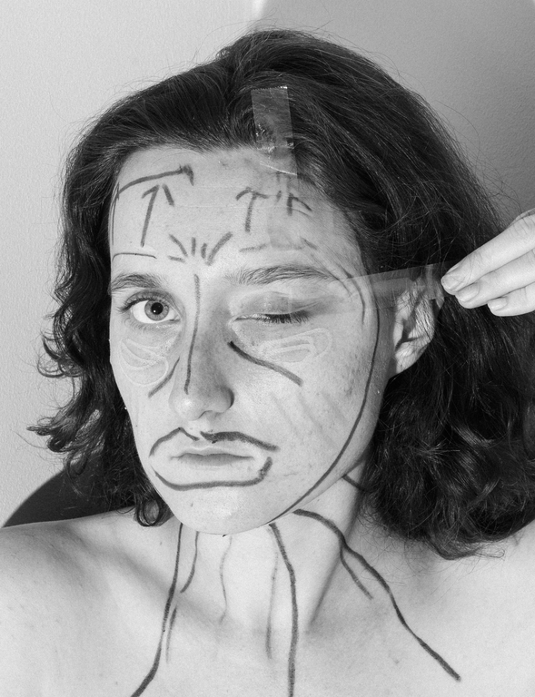 Karolina Wojtas, fot. selfie Zdjęcie przedstawia kobietę, która ma twarz pokrytą rysunkami w kształcie strzałek. Lewe oko ma zaklejone taśmą samoprzylepną. Fotografia jest czarno-biała.