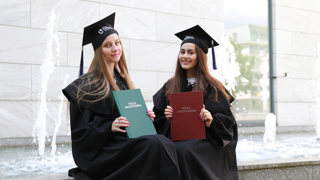 Absolwentki trzymające prace magisterskie