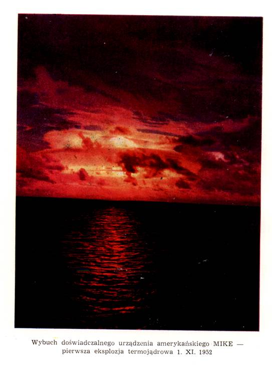 Na zdjęciu widoczny jest ciemny krajobraz morski oświetlony intensywną, czerwoną poświatą na niebie. Horyzont dzieli obraz na dwie części: górną z chmurami i dolną z powierzchnią wody. Niebo ma głęboki czerwony i pomarańczowy kolor, a chmury są nieregularne i miejscami bardzo jasne, jakby podświetlone od wewnątrz. Na powierzchni morza widać odbicie czerwonego światła, które tworzy pionowy pas świetlny na falującej wodzie. Reszta wody pozostaje prawie czarna. Cała scena jest silnie kontrastowa i ma dramatyczny charakter. Pod zdjęciem znajduje się podpis informujący, że fotografia przedstawia wybuch doświadczalnego amerykańskiego urządzenia o nazwie „Mike” – pierwszą eksplozję termojądrową, która miała miejsce 1 listopada 1952 roku.