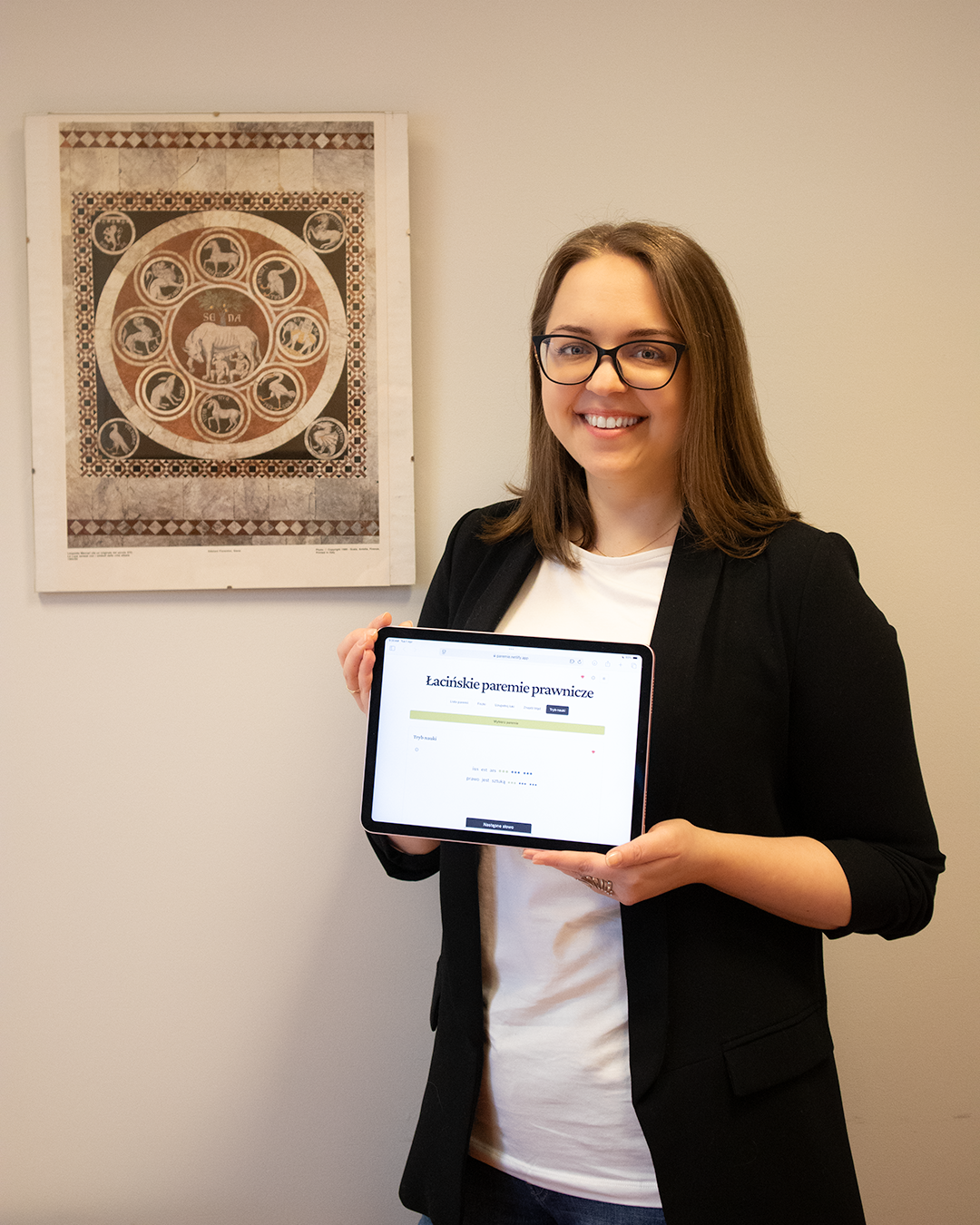 A woman with long hair wearing a black jacket and holding a tablet