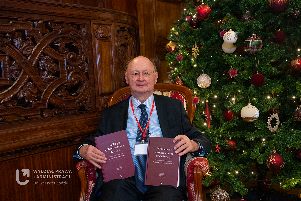 Mężczyzna w garniturze trzymający dwie księgi.