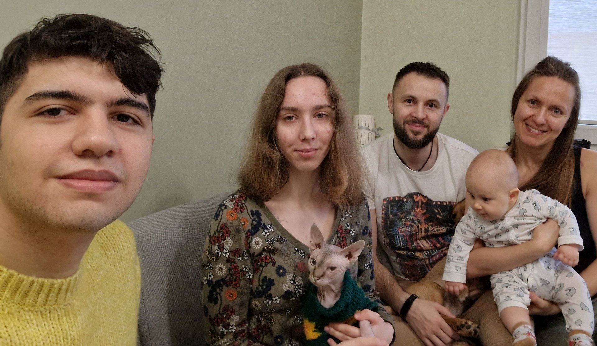 Participants of the University of Lodz "Christmas Guest" campaign, two men and two women smiling at a child, one of the women is holding a baby