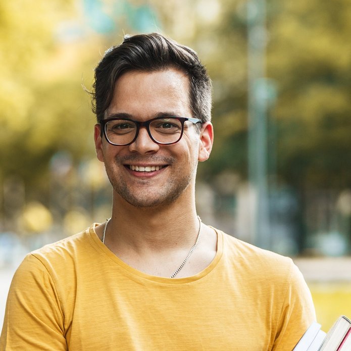 kolorowe zdjęcie przedstawiające młodego mężczyznę trzymającego książki