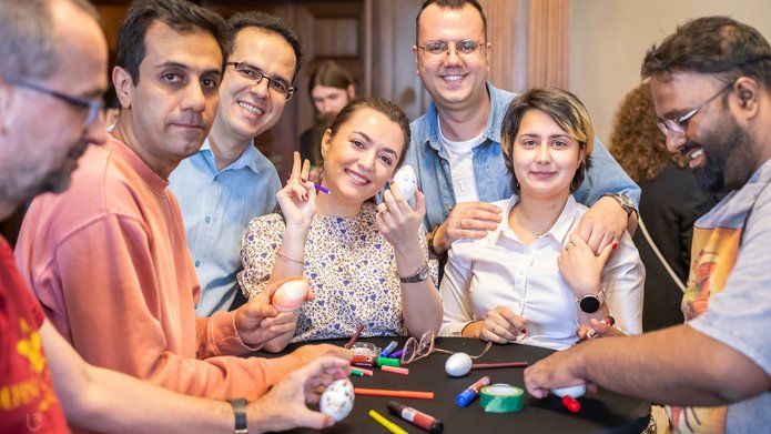 Osoby z różnych krajów ozdabiające pisanki przy jednym stoliku