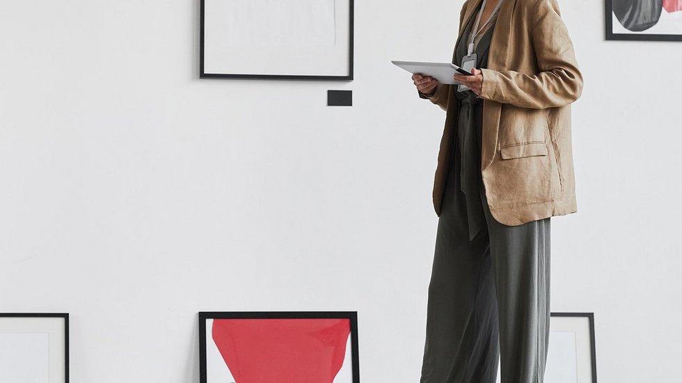 a decorative element: a decorative element: a woman looking at works of art hanging on the wall and standing on the floor