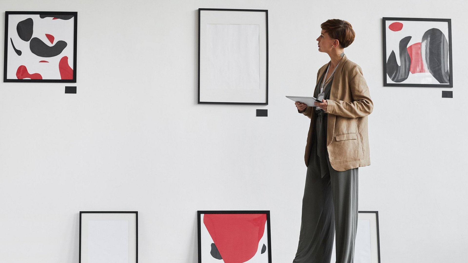 a decorative element: a woman looking at works of art hanging on the wall and standing on the floor