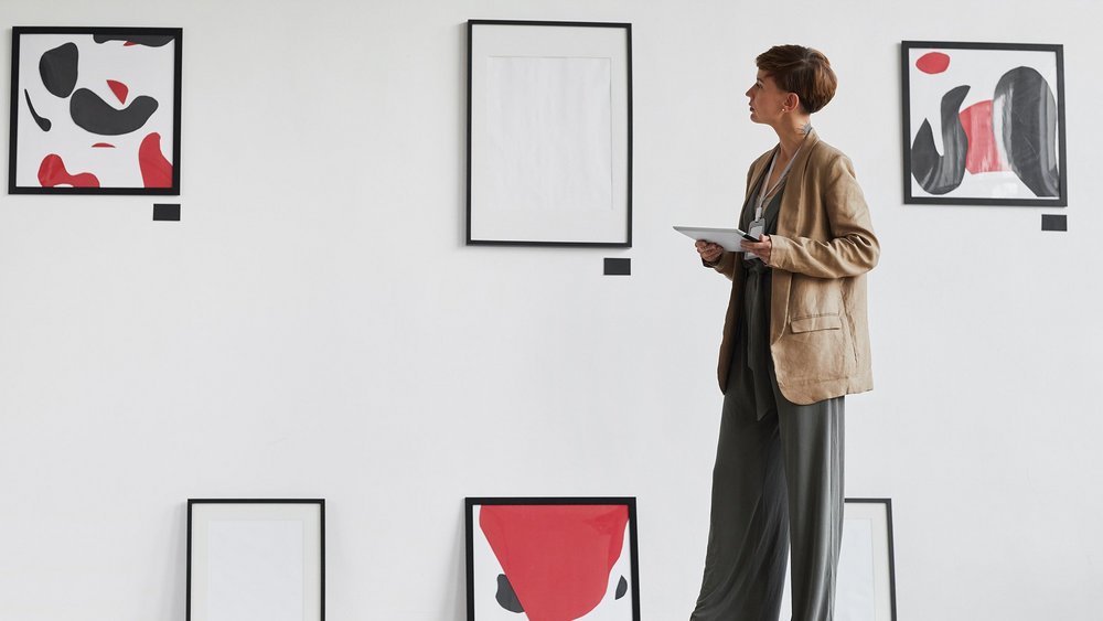 a decorative element: a woman looking at works of art hanging on the wall and standing on the floor