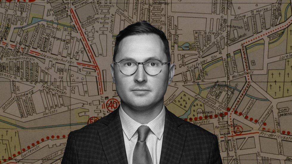 Dr Adam Sitarek na tle mapy łódzkiego getta