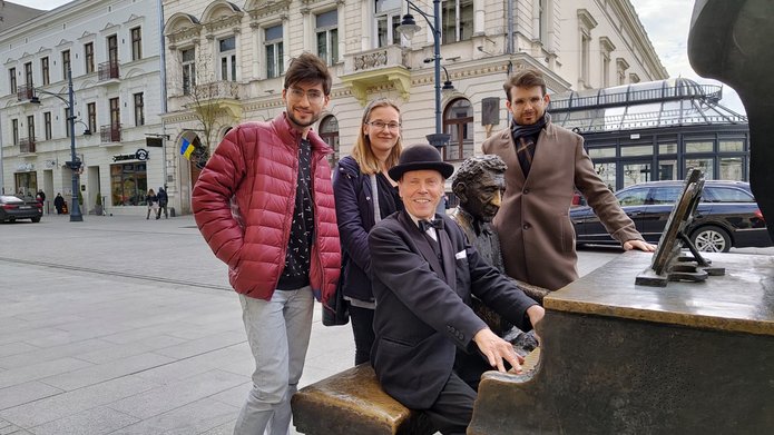 Troje studentów i artysta Marcin Szytenchelm przy pomniku Fortepian Rubinsteina