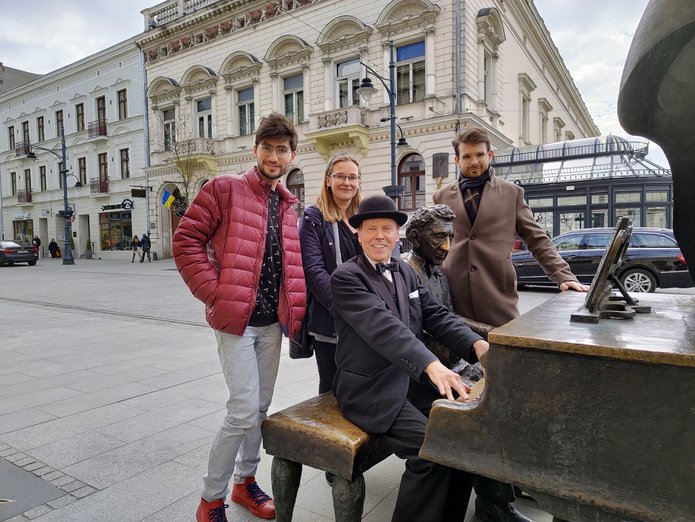 Troje studentów i artysta Marcin Szytenchelm przy pomniku Fortepian Rubinsteina