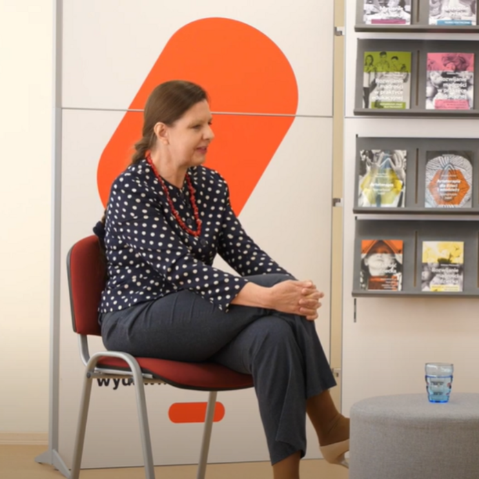 Kobieta w granatowym ubraniu siedząca na krześle