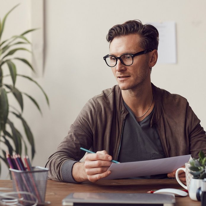 a decorative element: a young man wearing glasses sitting at a desk and working