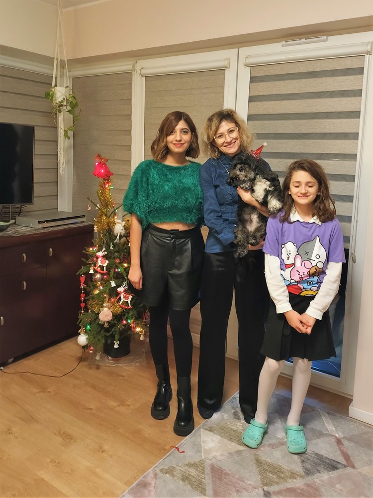 Participants of the University of Lodz "Christmas Guest" campaign, three smiling women and a dog in a Santa's hat