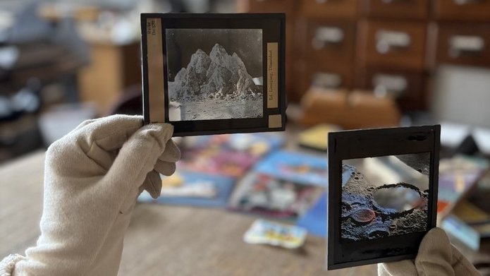 The photo shows a messy interior and gloved hands holding old negatives