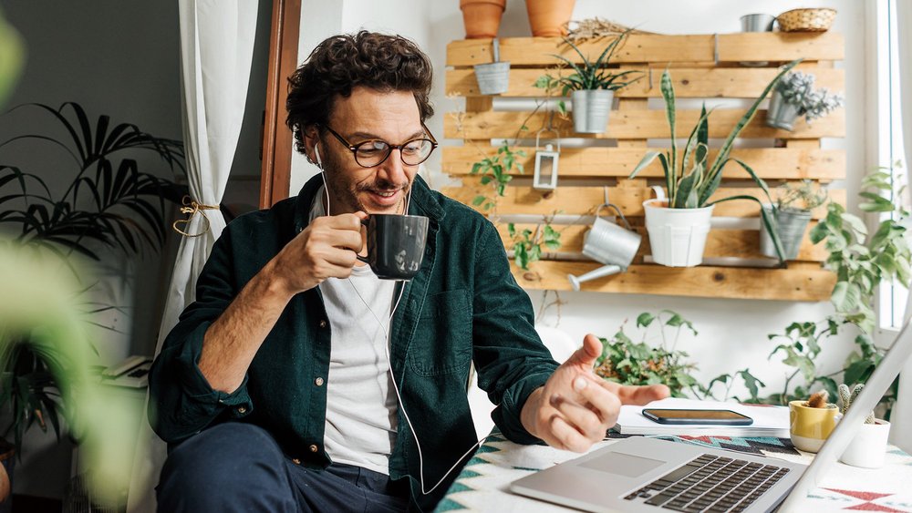mężczyzna z kawą w dłoni pracuje przy laptopie