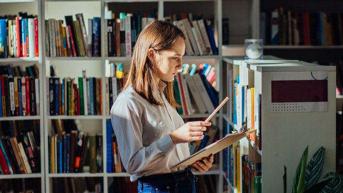 Dziewczyna szuka książek w bibliotece