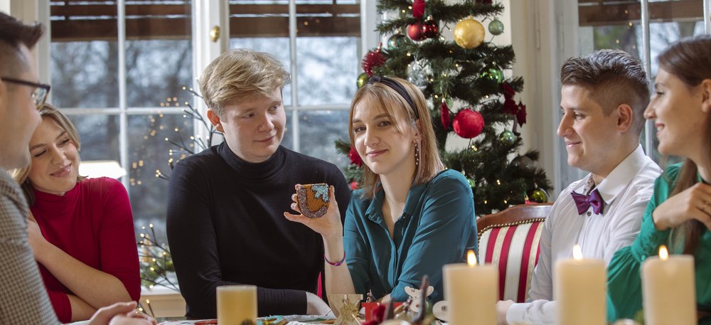 a female student holding a gingerbread cookie with the logo of the University of Lodz in her hand