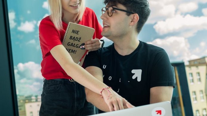 a girl and a boy sitting at a laptop