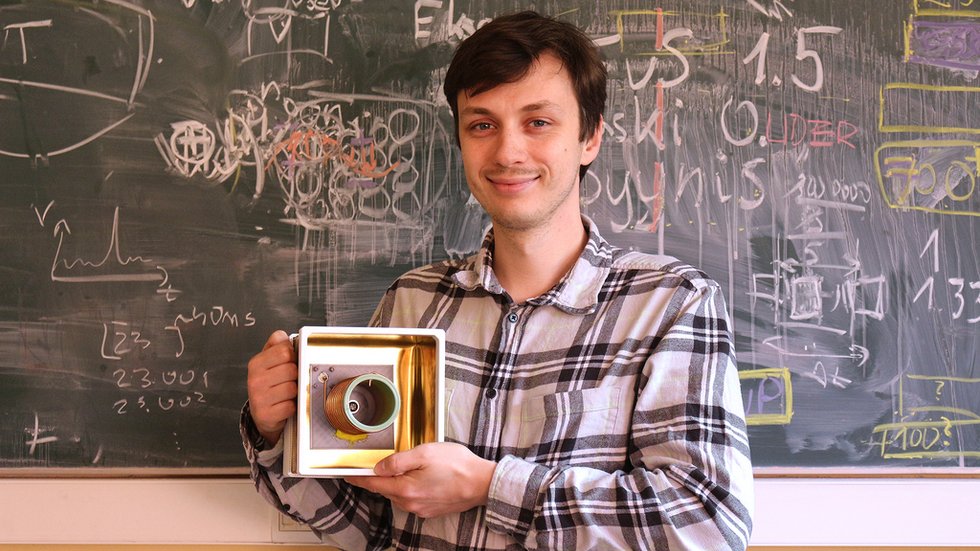 Maciej Ślot with a sensor against the background of a board with patterns written on it