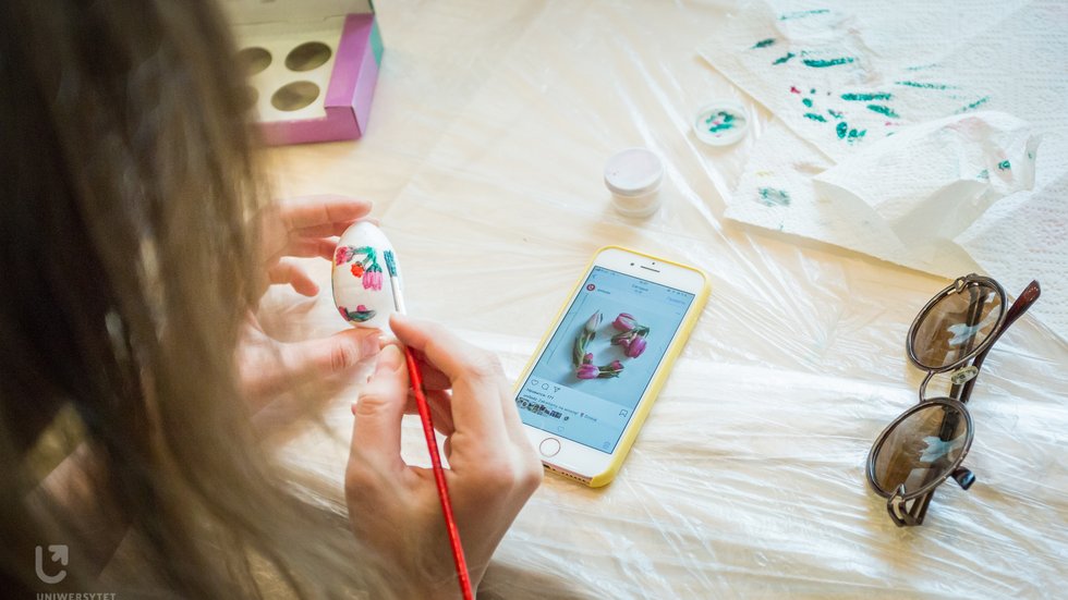 A woman with long hair painting an Easter egg