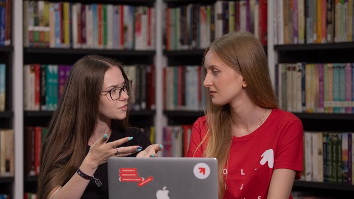 Dwie studentki dyskutują w bibliotece