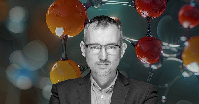 A portrait photo of Dr hab. Łukasz Półtorak, Associate Professor at the University of Lodz, against the background of balls symbolising molecules