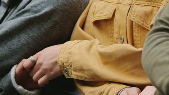 Osoby stojące obok siebie i trzymające się za ręce 