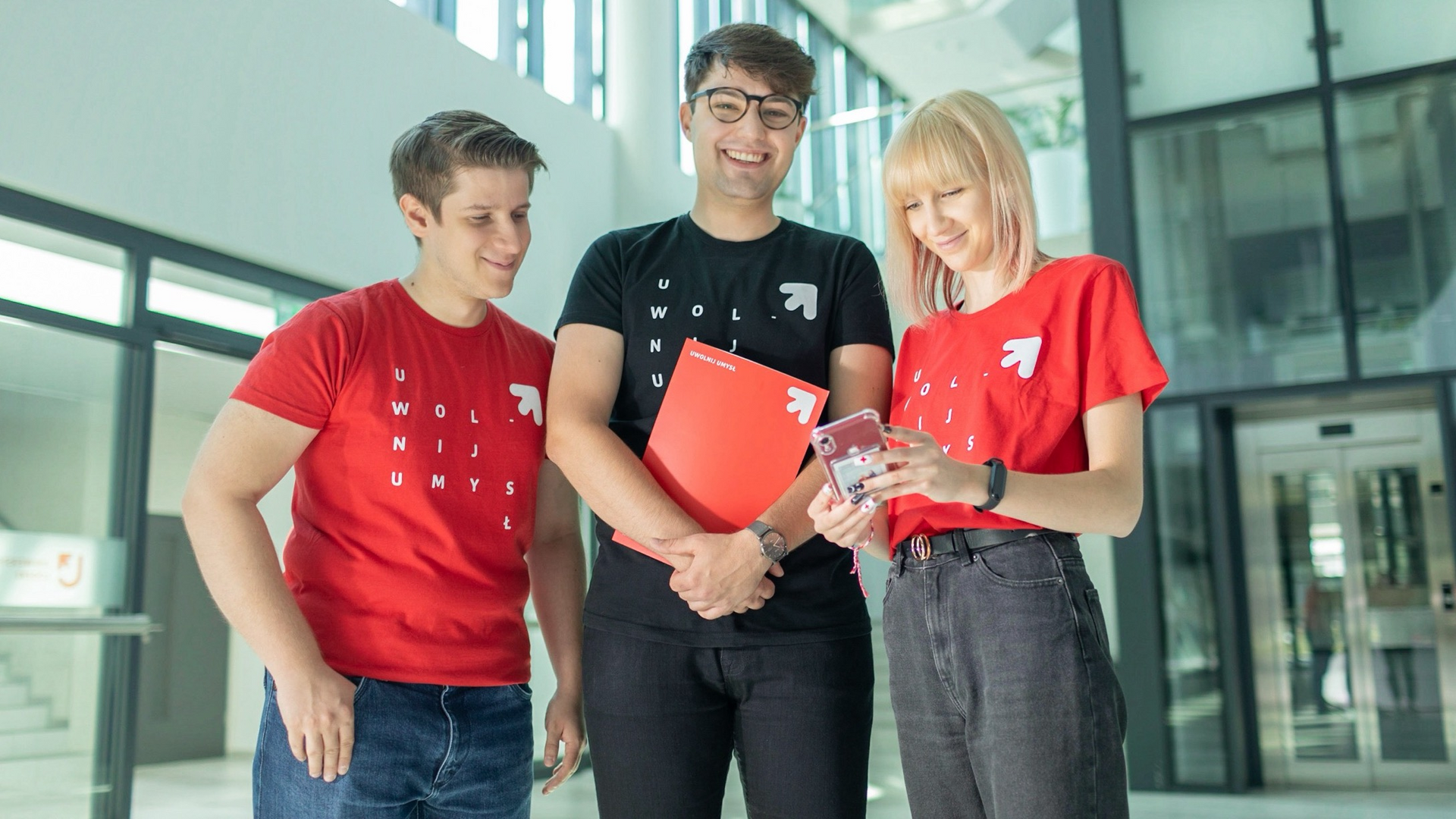 Troje studentów UŁ stojących z teczką na korytarzu wydziału
