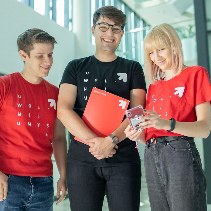 Troje studentów UŁ stojących z teczką na korytarzu wydziału