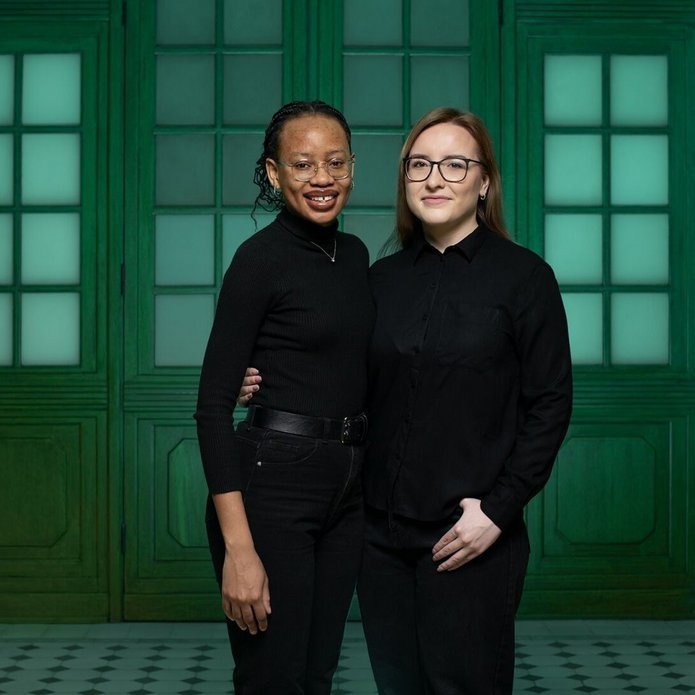 Two female students, i.e. UNIC Ambassadors at the University of Lodz, standing side by side on a green background