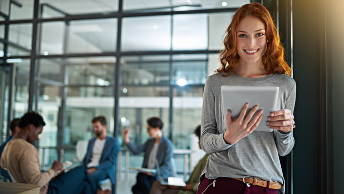 uśmiechnięta kobieta z rudymi kręconymi włosami trzymająca tablet