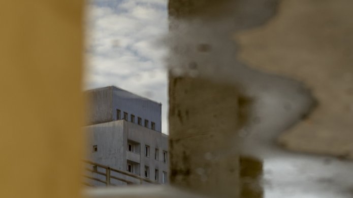 A photo: reflection of a building in a puddle