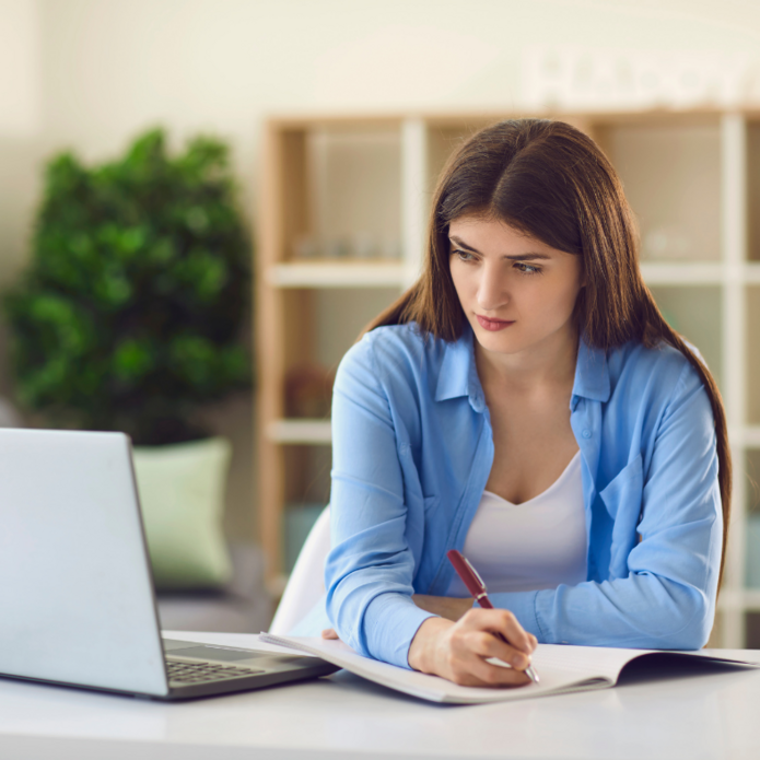 Młoda kobieta robi notatki. Zdjęcie poglądowe.