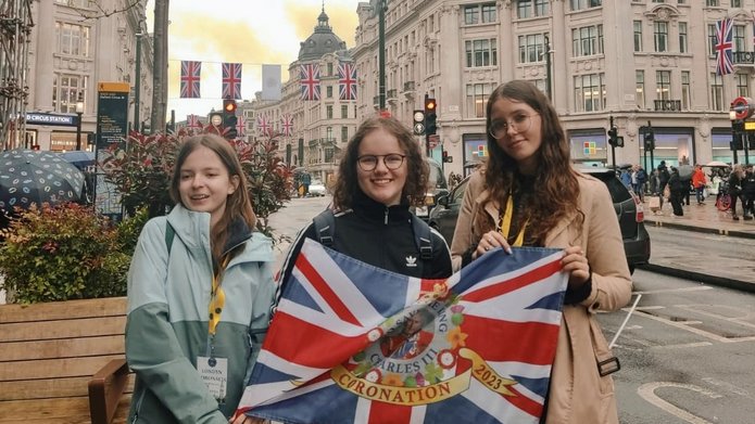 3 uczennice BISUL trzymające flagę brytyjską stojące na ulicach w Londynie