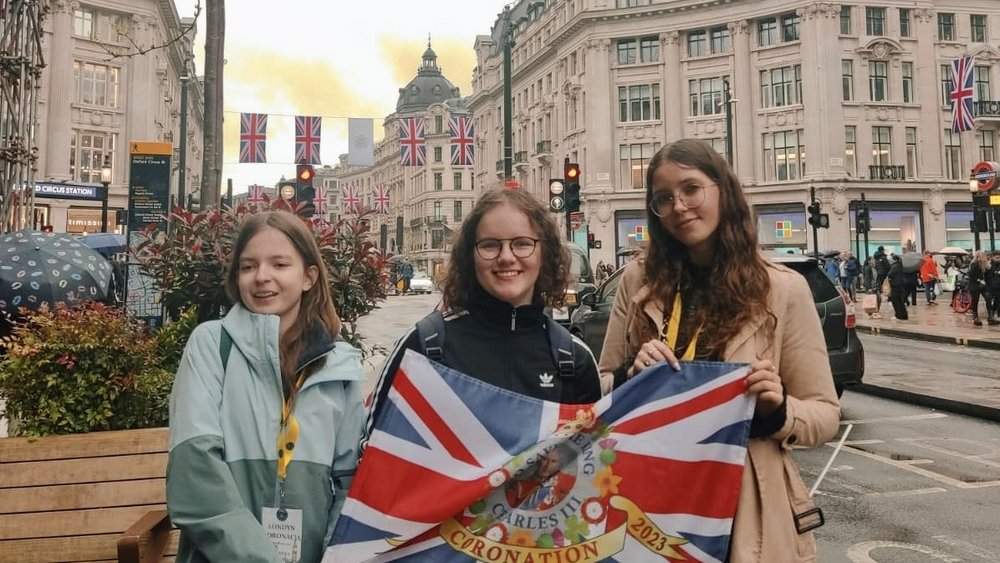 3 uczennice BISUL trzymające flagę brytyjską stojące na ulicach w Londynie