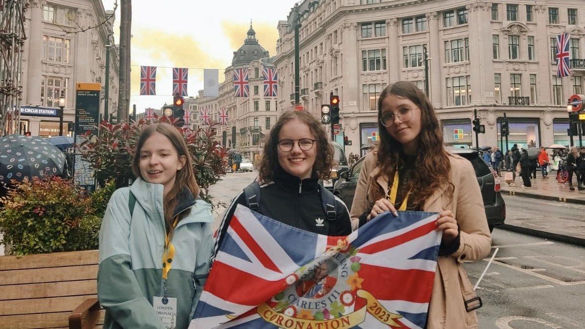 3 uczennice BISUL trzymające flagę brytyjską stojące na ulicach w Londynie