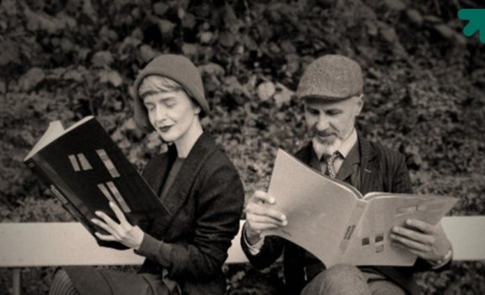 dwie osoby stylizowane na lata dwudzieste czytające gazetę 