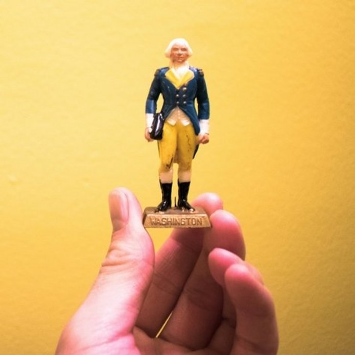 A hand holding a figurine of George Washington