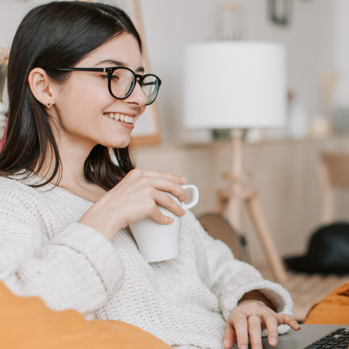 Uśmiechnięta dziewczyna patrzy w ekran komputera. Zdjęcie poglądowe.