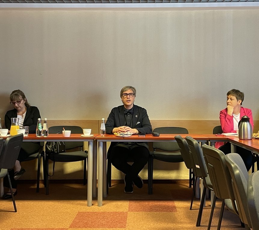 grupa ludzi siedząca przy stołach z poczęstunkiem