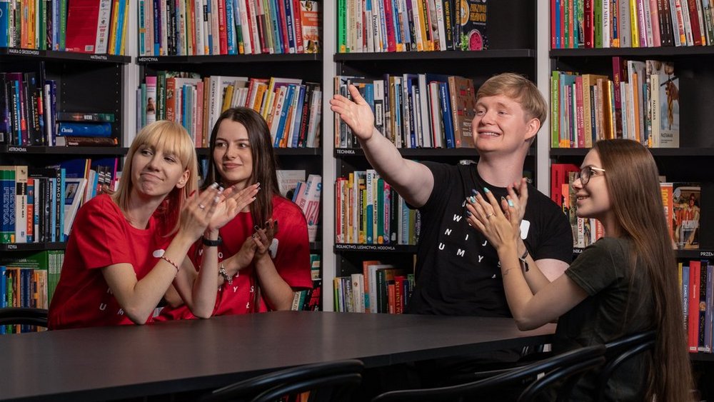 a group of students who are sitting at a table in the library and discussing