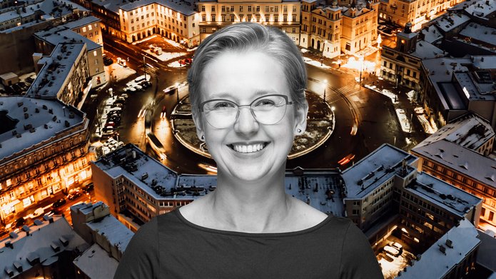 Dr Aleksandra Mroczek-Żulicka on the background of the Freedom Square in Lodz seen from a bird's eye view at night in winter weather with snow on the roofs of buildings